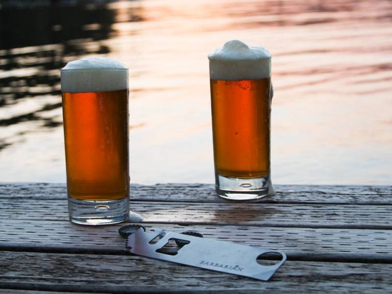 Two glasses of beer with a Barbarian Bar Tools' Simple Tool lying in front of them.