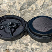 Beyerdynamic PHONUM with open travel case showing the top of the speakerphone and the charging cable inside the travel case