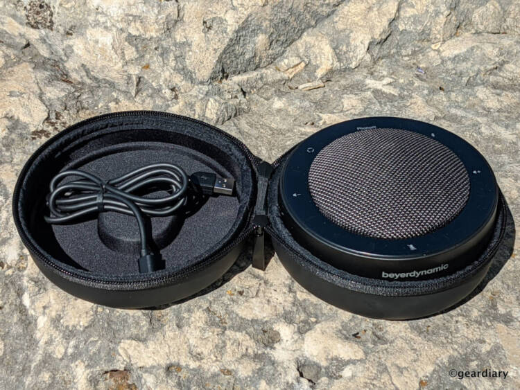 Beyerdynamic PHONUM with open travel case showing the top of the speakerphone and the charging cable inside the travel case