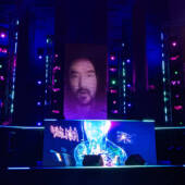A stage with dramatic lighting and Steve Aioki's face on the screen.