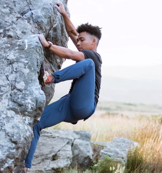 Man climbing a rock wall while wearing Coalatree Trailhead Pants.