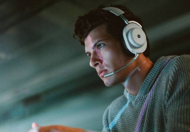 Man wearing the Master & Dynamic MG20 Wireless Gaming Headphones in white.