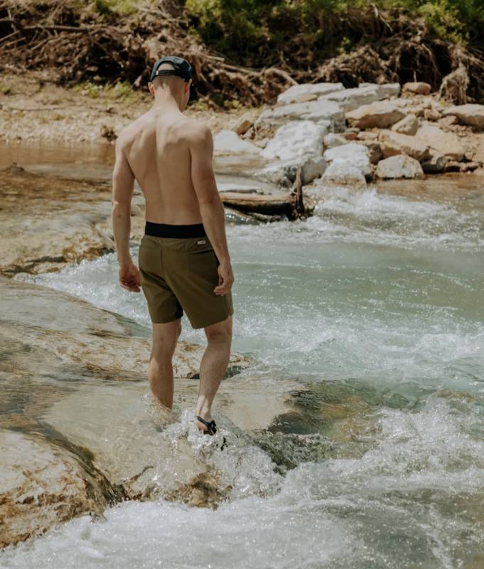 Man getting into a river wearing a pair of LIVSN Reflex Shorts for Men