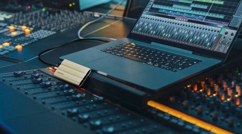 The Samsung T7 Shield Portable SSD sitting in front of a laptop near a mixing board.