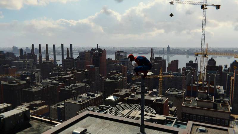Scene from Marvel's Spider-Man Remastered; Spidey is perched up high and looking down at the city.