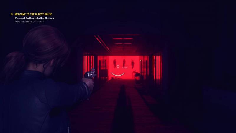 Jesse has her gun drawn as she walks down a long hall with a red light at the end