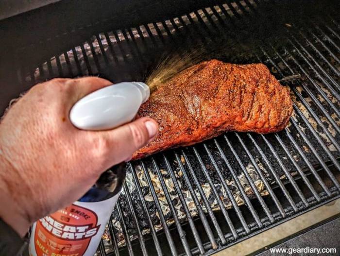 Spraying a beef tri-tip with Meat Sweats BBQ Spritz Bull Spritz in the pit. 