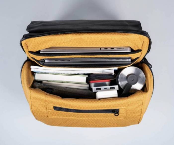 The interior of the WaterField Miles Laptop Backpack with an assortment of mobile devices, books, and other gear inside the main compartment. 