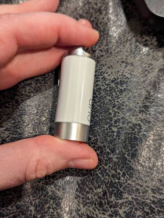 The author holding a single Arlo Safe device; it is a less than 2" long white cylinder with silver ends.