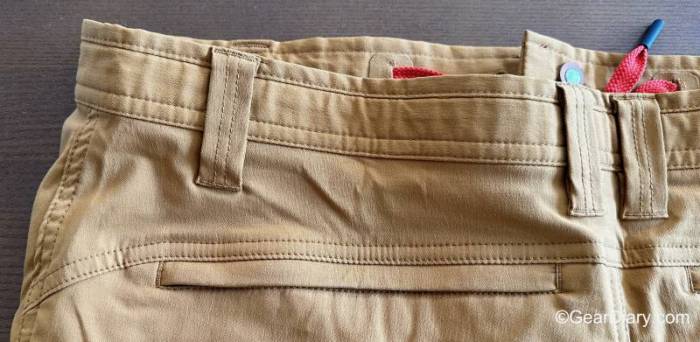 Closeup detail of the rear top left of a pair of khaki LIVSN Ecotrek Trail Shorts showing the waistband, belt loops, and left rear pocket. 