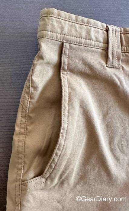 Detail of the right front pocket on a pair pf khaki LIVSN Ecotrek Trail Shorts showing the waistband, belt loop, and slash pocket. 