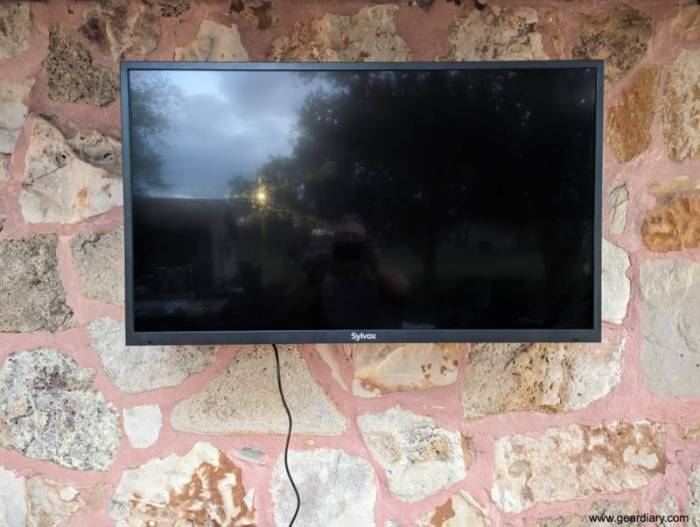 The mounted Slyvox 43" Outdoor TV on the author's home's exterior rock wall. 