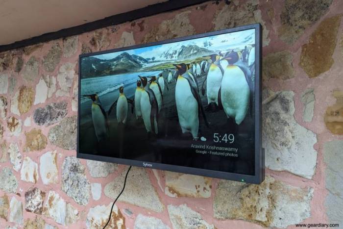The Slyvox 43" Outdoor TV is turned on and showing the weather with a group of penguins on the screensaver