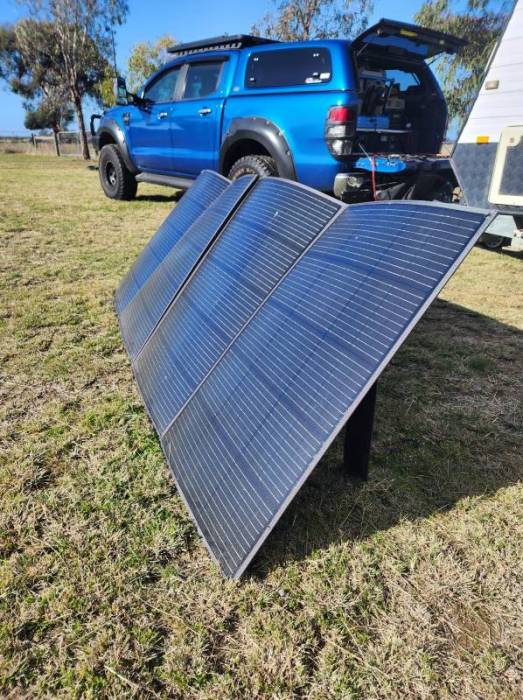 The DCV solar panel sits to the side of a blue truck with an RV attached