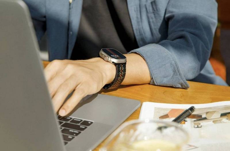 A person wearing the Pitaka Carbon Fiber Apple Watch Band (Rhapsody Version) on their wrist as they type on a MacBook
