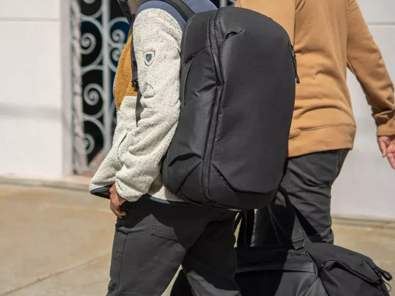 A person wearing the Peak Design Travel Backpack 30L and carrying a duffel.