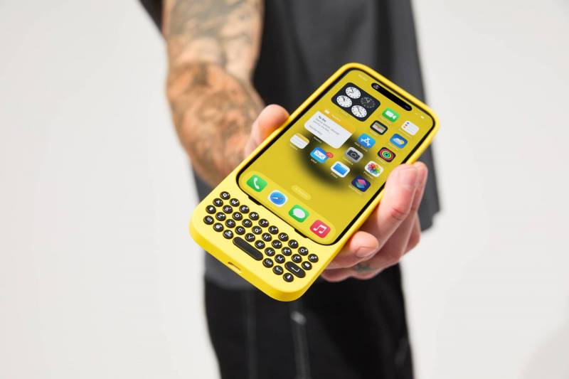 A man holds an iPhone in a yellow Clicks Creator Keyboard with the keyboard facing toward the viewer