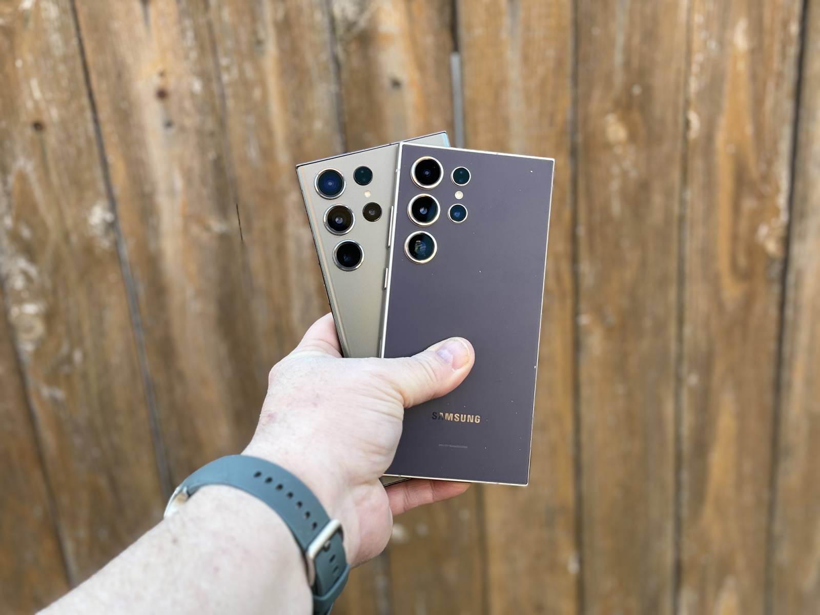 A man holds two phones against a wall.