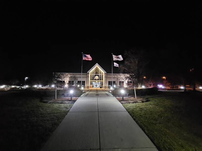 Flags wave outside a building at night.