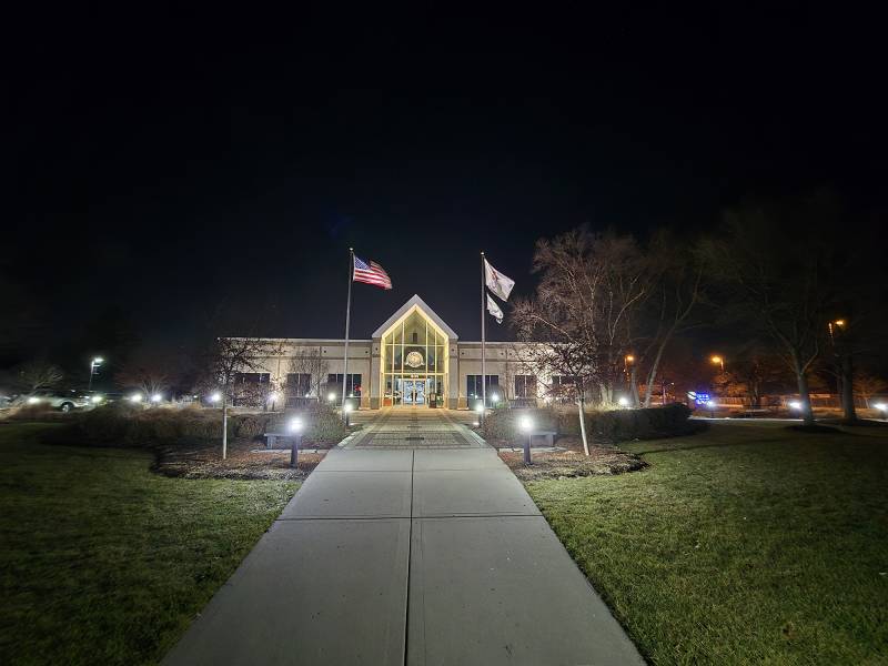 Flags wave outside a building at night.