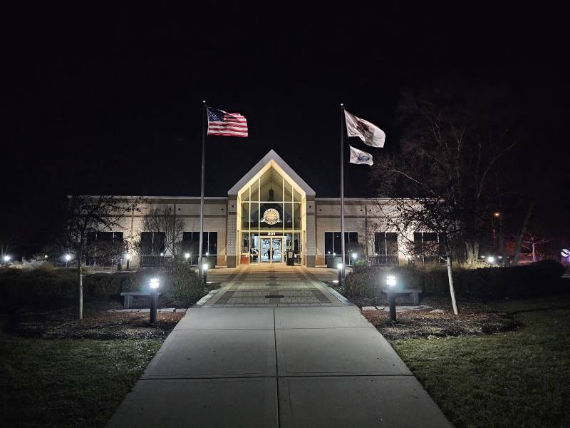 Flags wave outside a building at night.