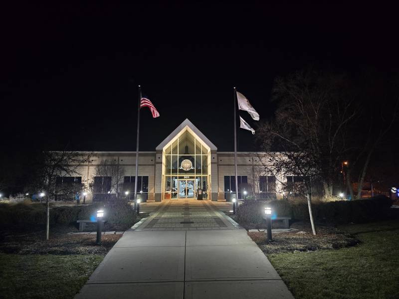 Flags wave outside a building at night.