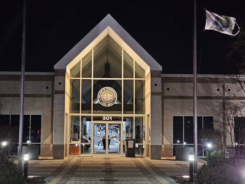 Flags wave outside a building at night.