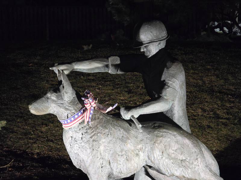 A statue shows a man and dog crouching.