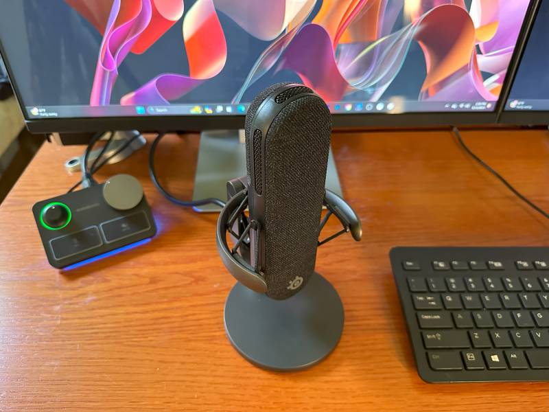 SteelSeries Alias Pro XLR Mic on a desktop sitting in front of a monitor and next to the author's keyboard.
