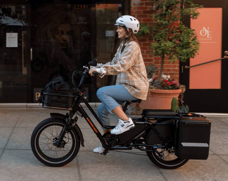 Woman riding the Rad Power Bike's RadWagon 5 Electric Cargo Bike in black.