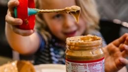 Child using the Simple Spread to get peanut butter out of a jar.