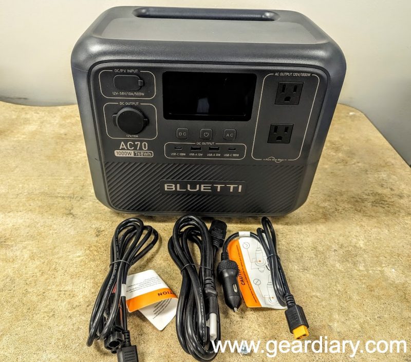 Front of the BLUETTI AC70 Portable Power Station with the three included charging cables lying in front of it.