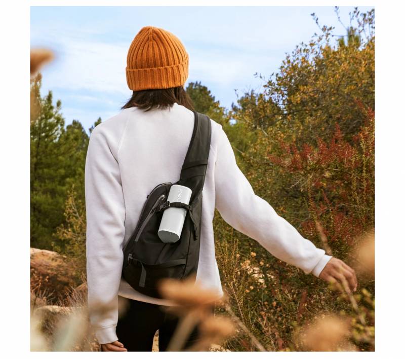 Person carrying a Sonos Roam 2 Speaker on the back of their pack.