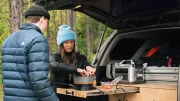 A couple cooking out of the back of their vehicle on the Stoke Voltaics Nomad Cooking System