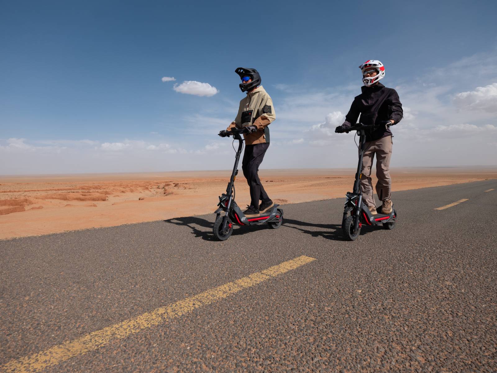 Two people riding their Segway ZT3 Pros down a highway next to a desert area