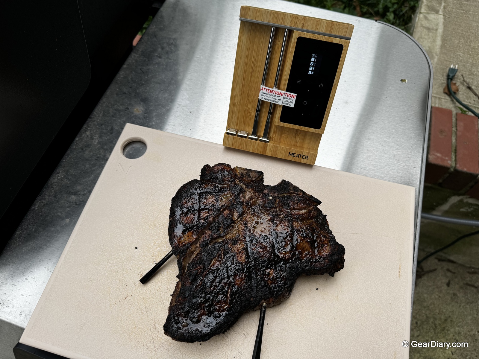 The finished Porterhouse steak sitting on a cutting board in front of the MEATER Pro XL