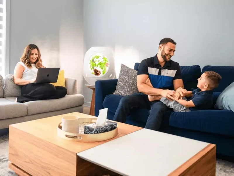 A family sitting in their living room with a Plantaform Smart Indoor Garden nearby.