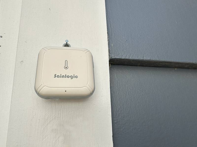 Sainlogic SA1 Wi-Fi Smart Weather Station sensor installed on a north-facing exterior wall at the author's home.