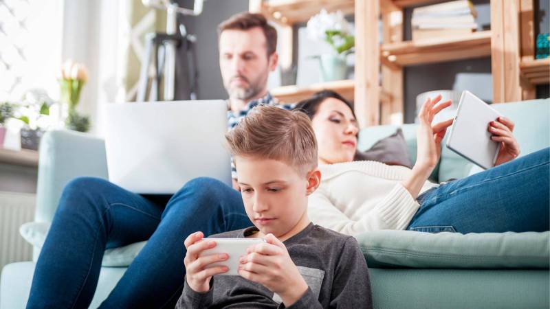 A family together while all on their devices. 