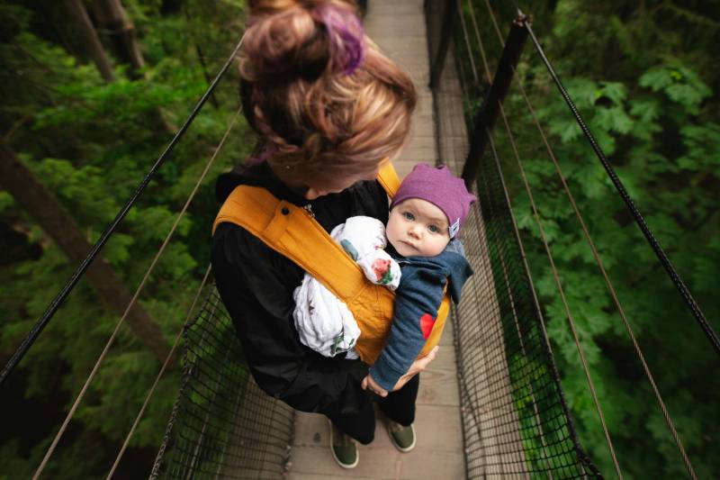 Woman carrying her baby on a bridge.