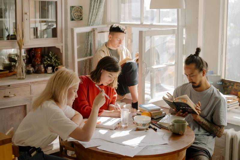 Photo of students gathered around a table in an apartment.