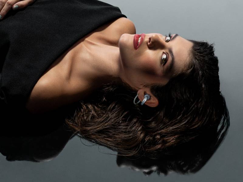 The Brilliant Collection - woman with dark hair and a dark top lying down with the moto buds loop in her left ear.