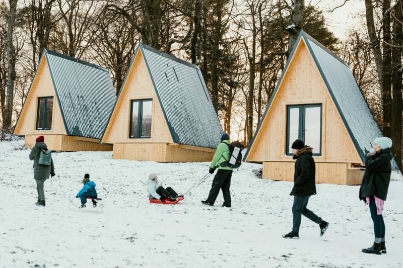 Gear Diary’s 2025 Holiday Gift Guide & Giveaway: Trail-Tested Gifts for Campers, Overlanders, and Outdoors Diehards 1 People walking by a snowy family retreat.