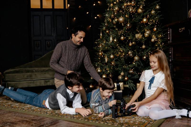 A family in front of the tree playing with holiday toys