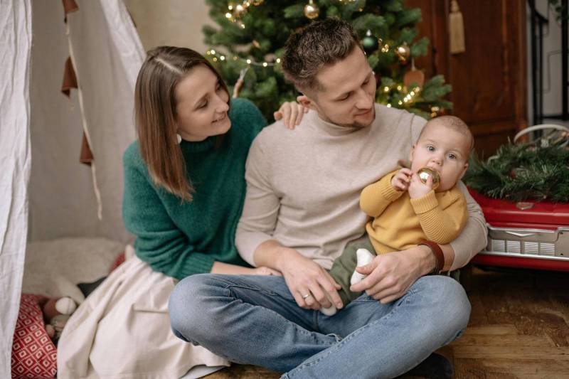Gear Diary’s 2025 Holiday Gift Guide & Giveaway: Clever, Comforting, and Sanity-Saving Gifts for Parents 1 Parents with baby in front of Christmas tree