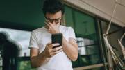 Photo of a man looking at his smartphone in frustration